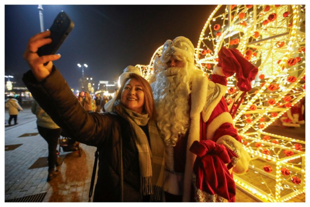 A woman captures a festive moment with a participant portraying as Ayaz Ata (Father Frost), the Kazakh equivalent of Santa Claus, during a lively city procession marking the Christmas season in Almaty, Kazakhstan on December 25, 2023. (Image: Reuters)