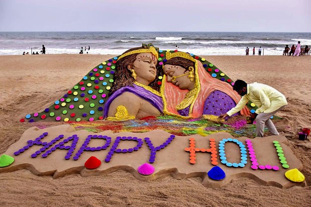 Sand artist Sudarshan Pattnaik creats a sand art on the occasion of Holi, at Puri beach, Odisha (PTI)