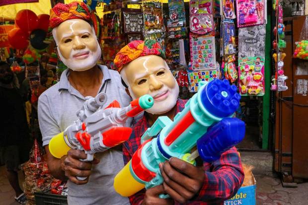 Vendors wearing masks of Prime Minister Narendra Modi hold water guns at a shop ahead of the festval of Holi, in Nagpur. (PTI Photo)