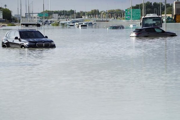 Vehicles sit abandoned in floodwaters covering a road in Dubai, UAE