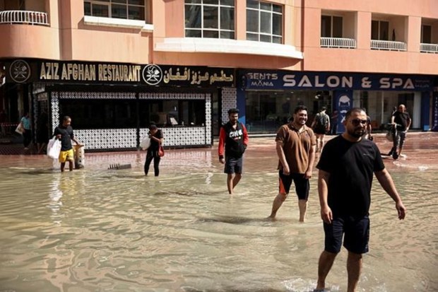 People walk through flood water caused by heavy rains in UAE
