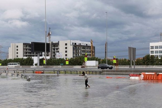 A person walks through water in a flooded street following unprecedented rains