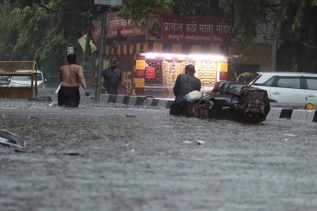 People are seen wading through a waterlogged road amid rains, in New Delhi, Friday morning on June 28, 2024. (Photo source: PTI)
