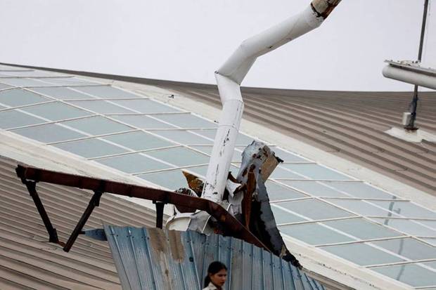 In this picture a woman can be seen standing in front of the portion of a damaged canopy at the Indira Gandhi International Airport. (Photo source: PTI)