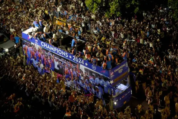 Players of the T20 World Cup-winning Indian cricket team with the championship trophy acknowledge fans during their open bus victory parade. (PTI)