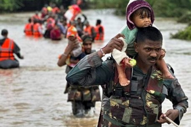 During a rescue effort of trapped individuals after intense rainfall in flood-affected areas of Jamnagar, Rajkot and Dwarka, an army personnel is seen carrying a child. (PTI Photo)
