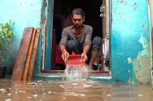 On Thursday, as the flood situation in low-lying districts of Vadodara, Gujarat, grew worse, a man empties water from his home. (PTI Photo)