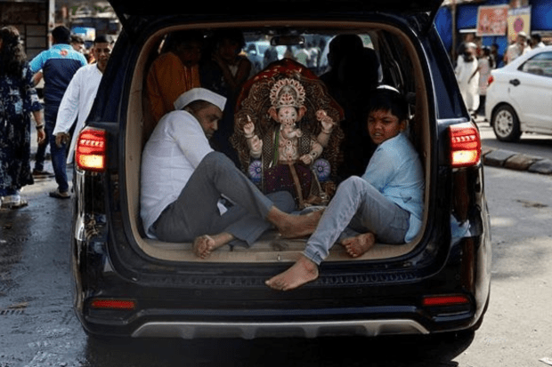 People travel in a car with an idol of the Hindu god Ganesh on the first day of the ten-day long Ganesh Chaturthi festival, in Mumbai. (Photo: Reuters)