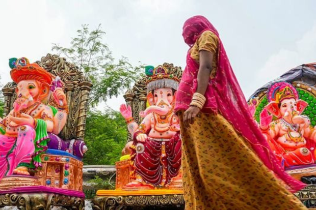 A woman walks past clay idols of Lord Ganesh, being displayed for sale, ahead of Ganesh Chaturthi festival, in New Delhi. (Photo: PTI)