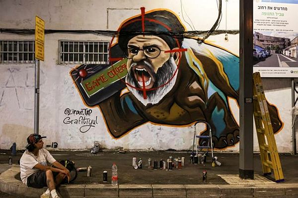 Israeli graffiti artist Maayan, from the Grafitiyul group, rests after she finished working on a graffiti of Hezbollah leader Sayyed Hassan Nasrallah after Israel's military confirmed it had eliminated him in a Beirut airstrike, in Tel Aviv, Israel, September 29, 2024. REUTERS