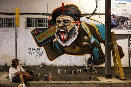 Israeli graffiti artist Maayan, from the Grafitiyul group, rests after she finished working on a graffiti of Hezbollah leader Sayyed Hassan Nasrallah after Israel's military confirmed it had eliminated him in a Beirut airstrike, in Tel Aviv, Israel, September 29, 2024. REUTERS