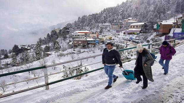 Tourist walk on a snow covered road after a fresh spell of snowfall, at Kufri. (Photo source: PTI)