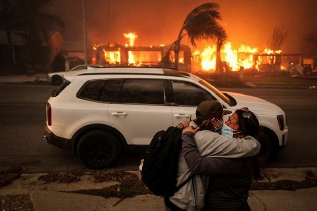 As powerful winds intensify the destructive wildfires in the Los Angeles area, people embrace while evacuating the Eaton Fire in Altadena, California, on January 8, 2025. (Image Source: Reuters)