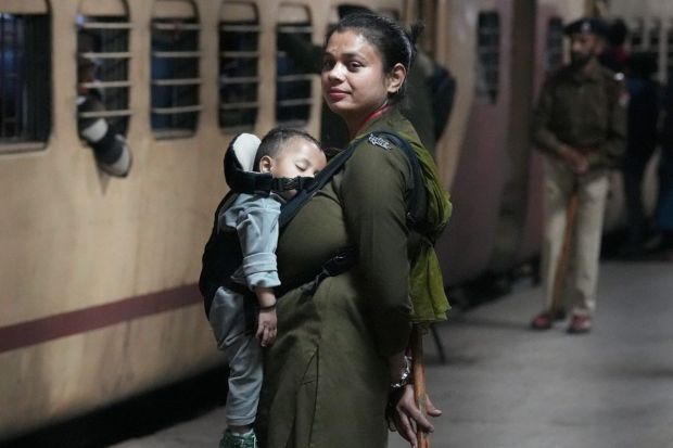 An RPF personnel carrying her child stands guard at the New Delhi Railway Station. (Image: PTI)