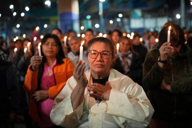 Faithful hold candles during Mass to honor the late Pope Francis under a highway bridge in the Carlos Mugica neighborhood of Buenos Aires, Argentina.