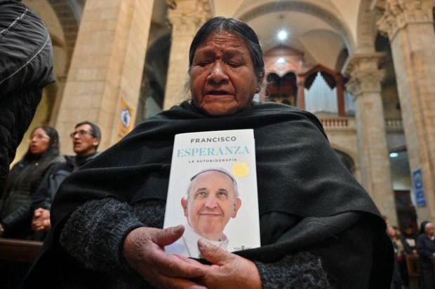 A woman holds a copy of the autobiography of Pope Francis, following the death of the pontiff, at the Metropolitan Cathedral of Our Lady of Peace, in La Paz.
