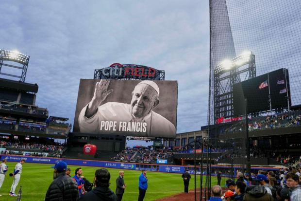 Fans and players stand during a moment of silence as a portrait of Pope Francis is displayed at Citi Field before a baseball game between the New York Mets and the Philadelphia Phillies on Monday in New York.