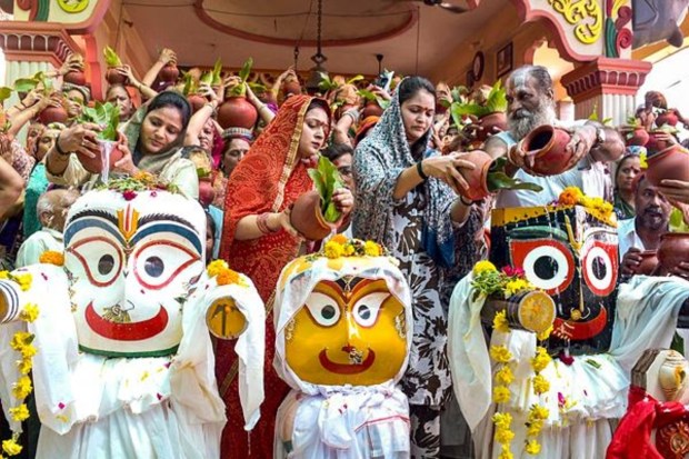 A priest and women devotees are performing the ritual bathing of Lord Jagannath, Balabhadra, and Subhadra at the Jagannath Temple in Surat, ahead of the Rath Yatra festival. (Image Source: PTI)
