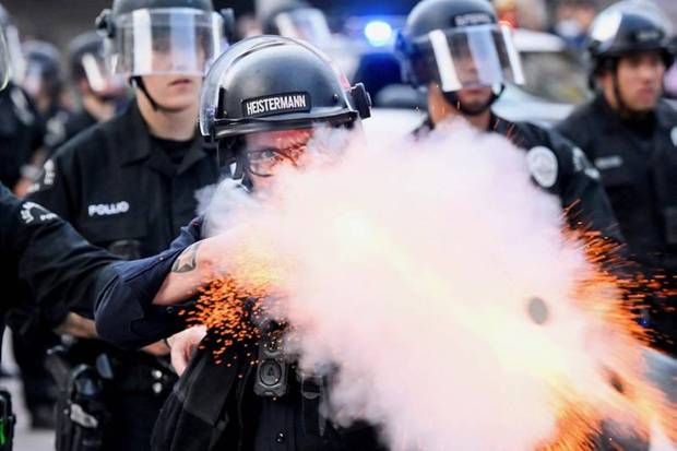 A law enforcement officer fires a less-lethal projectile during a protest. (Photo source: AP)