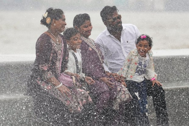 People get drenched by high tide waves at the Marine Drive promenade during the highest tide of this monsoon season in Mumbai. (PTI Photo)