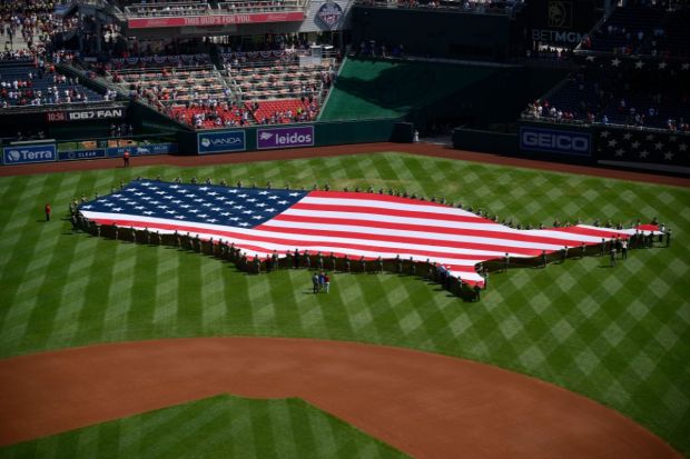 An American flag in the shape of the continental United States is displayed on the field before a baseball game between the Washington Nationals and the Boston Red Sox. (Image: AP)