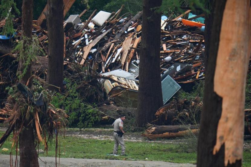 Officials comb through the banks of the Guadalupe River after the flash flood swept through the area.