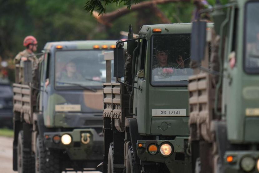 A military convoy drives on a road along the Guadalupe River following the flood.
