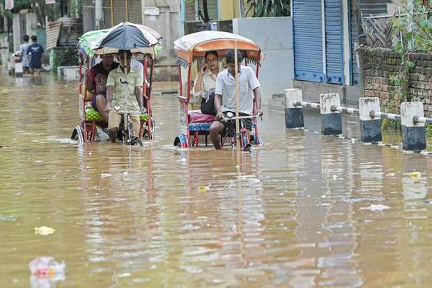 Rickshaw pullers take passengers through a severely waterlogged road in the Anil Nagar area following heavy rainfall in Guwahati on Tuesday (Photo source: ANI)