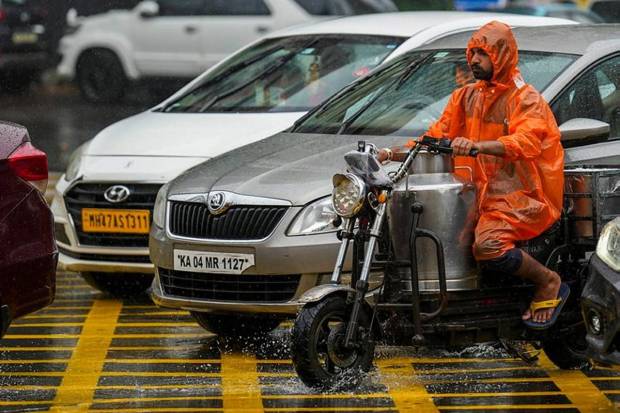 Porters pull their carts covered in plastic sheets during rain, in Mumbai, Maharashtra. (Photo source: PTI)