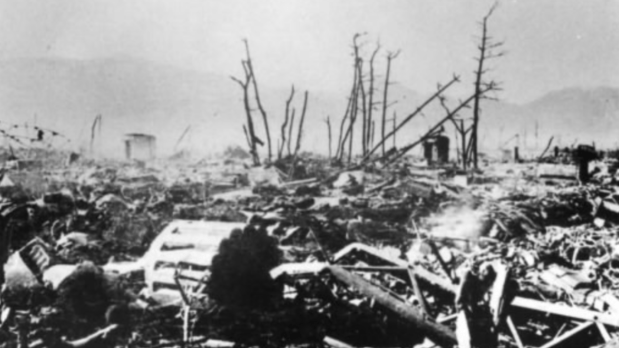 This picture, taken soon after the bombing, shows smouldering fires around the once bustling street. In the centre, back, is the Hiroshima Prefectural Commercial Exhibition Hall (now, the A-bomb Dome). This photo was taken on Hondori Street, facing north. A charred body lies at the bottom left corner. (Photo source: Hiroshima Peace Memorial Museum)
