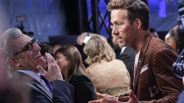 Eugene Levy (from left), sharp in a white suit, catches up with Ryan Reynolds at Roy Thomson Hall, both honoring Toronto legend John Candy at the festival’s acclaimed documentary premiere.