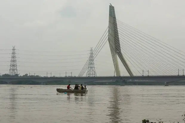 Visitors take a boat ride in the swollen Yamuna River at Wazirabad, in New Delhi. (Photo source: PTI)