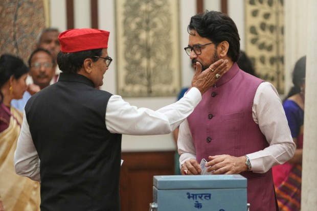 Ram Gopal Yadav, Indian lawmaker from Samajwadi Party, lightly pats Anurag Thakur, BJP member, as they arrive to cast their votes in the vice presidential election at Parliament House. (Image: AP)
